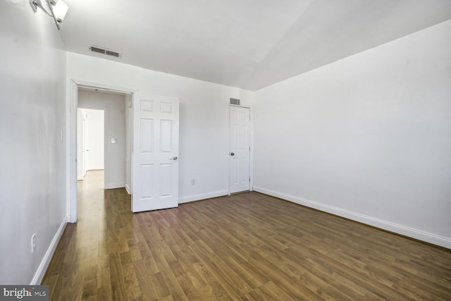 unfurnished bedroom with visible vents, dark wood finished floors, and baseboards