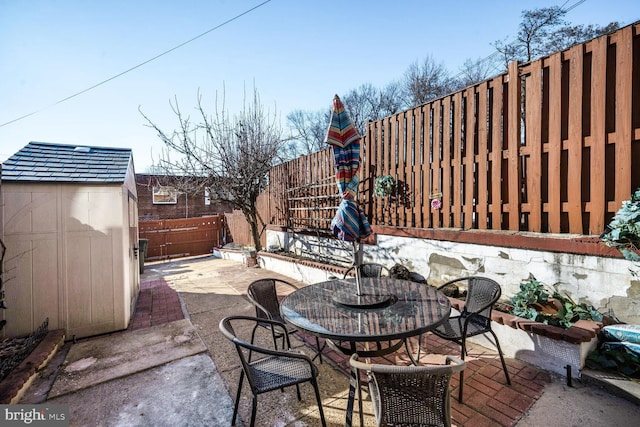 view of patio with a storage shed, a fenced backyard, and outdoor dining space