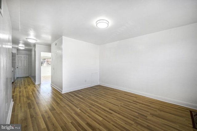 unfurnished room with dark wood-style flooring and baseboards