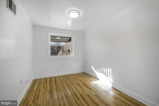 empty room featuring baseboards, visible vents, and wood finished floors