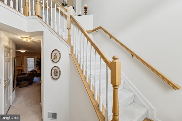 stairs featuring carpet flooring and a towering ceiling