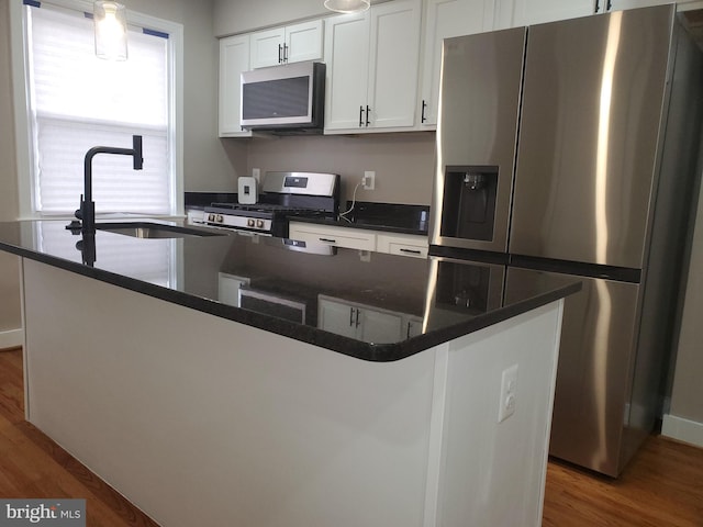 kitchen featuring stainless steel appliances, white cabinetry, a kitchen island with sink, and sink