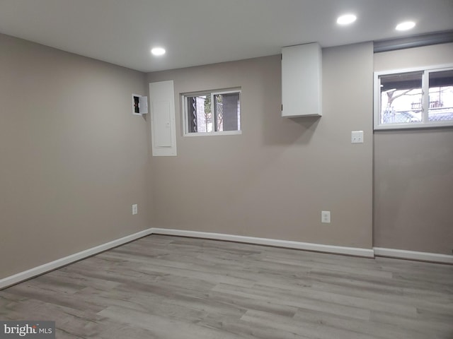 basement with electric panel and light wood-type flooring