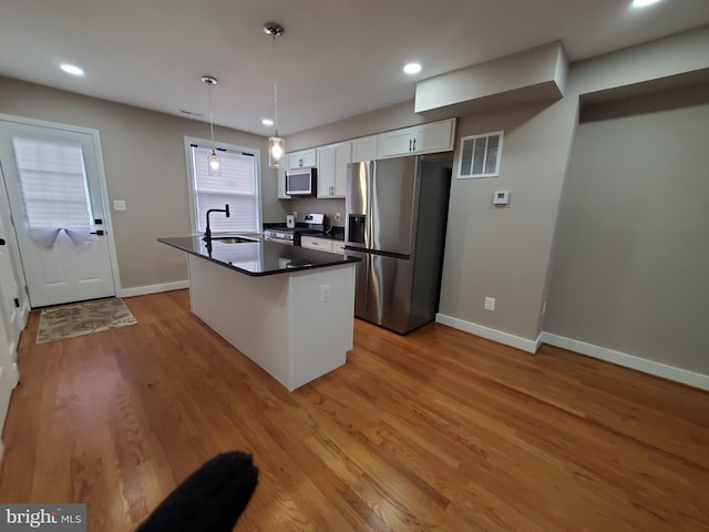 kitchen featuring hanging light fixtures, light wood-type flooring, appliances with stainless steel finishes, a kitchen island, and white cabinets