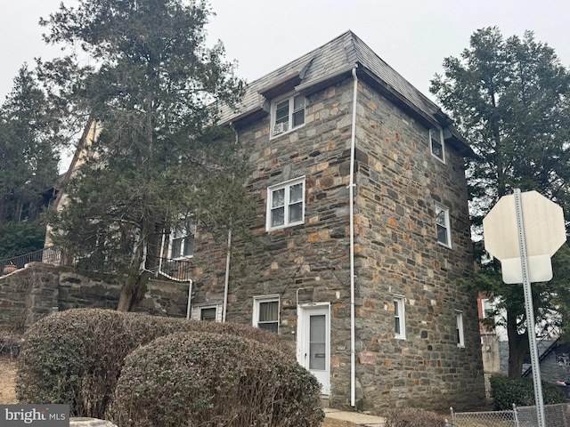 view of side of property featuring a high end roof and stone siding