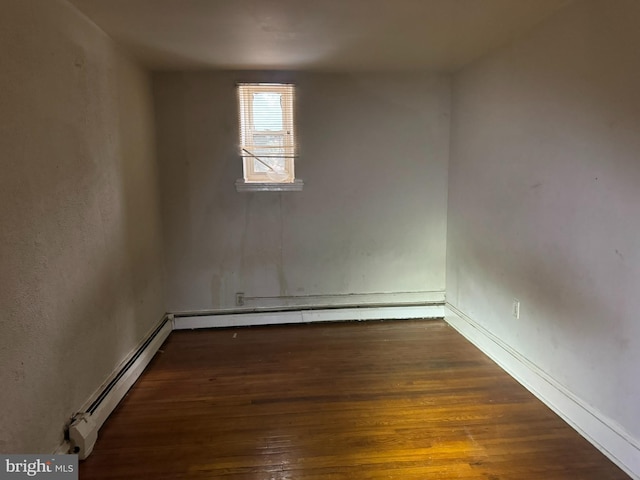 unfurnished room with wood finished floors, baseboards, and a baseboard radiator