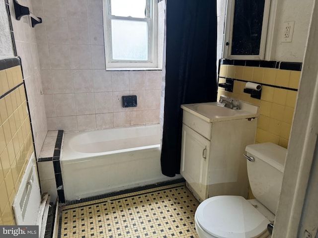 bathroom featuring vanity, tile walls, toilet, and bathtub / shower combination