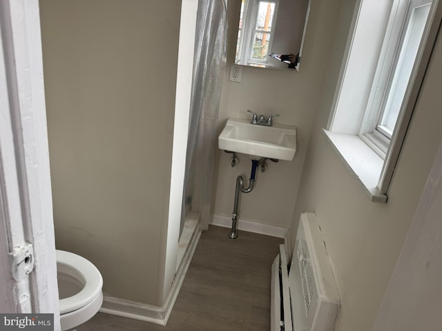 bathroom with a sink, baseboards, heating unit, and a shower stall