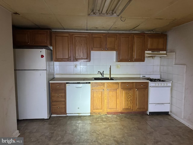 kitchen featuring a sink, white appliances, under cabinet range hood, and brown cabinets