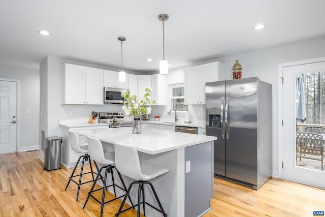 kitchen featuring a breakfast bar, white cabinetry, a center island, appliances with stainless steel finishes, and pendant lighting