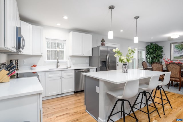 kitchen with hanging light fixtures, appliances with stainless steel finishes, and white cabinets