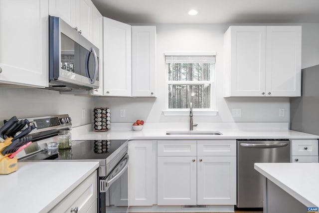 kitchen with appliances with stainless steel finishes, sink, and white cabinets