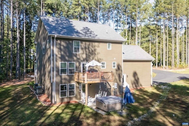 back of property with central AC unit, a yard, a hot tub, and a deck