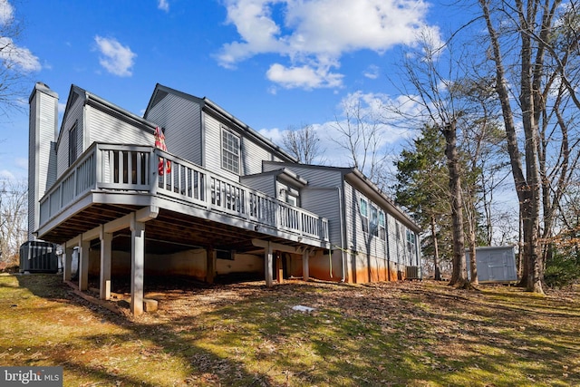 view of home's exterior with cooling unit, a wooden deck, and a storage shed