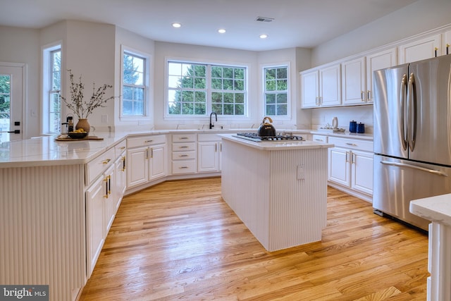 kitchen with stainless steel appliances, white cabinetry, and a kitchen island