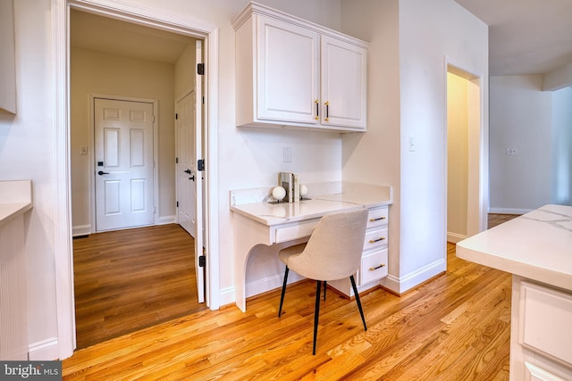 kitchen featuring built in desk, white cabinets, and light hardwood / wood-style flooring