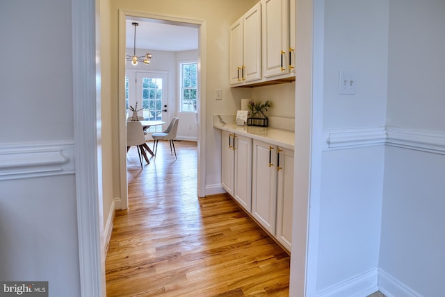 hall with light hardwood / wood-style floors and a chandelier