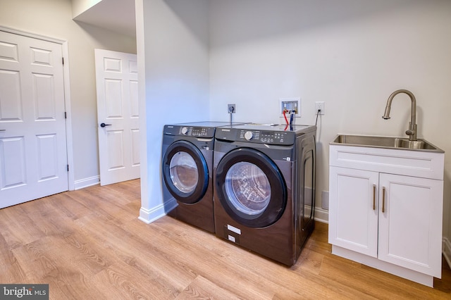 washroom featuring sink, cabinets, light hardwood / wood-style floors, and washer and dryer