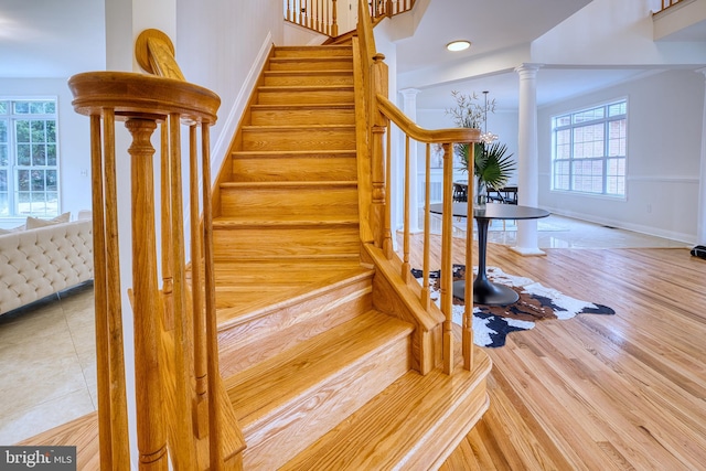 stairway with hardwood / wood-style flooring, plenty of natural light, and decorative columns