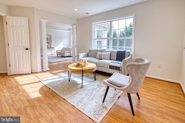 living room with decorative columns and light wood-type flooring