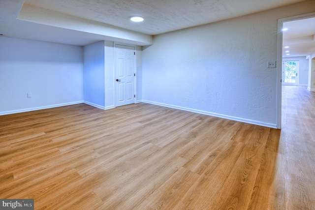 basement with a textured ceiling and light hardwood / wood-style floors