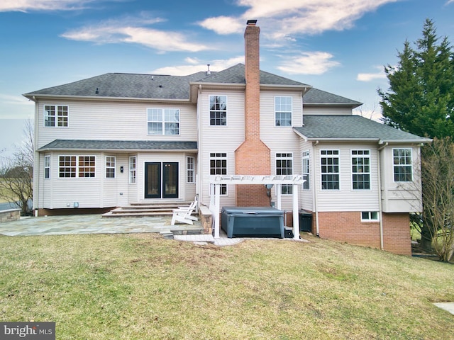 rear view of house featuring a yard, a hot tub, a pergola, and a patio