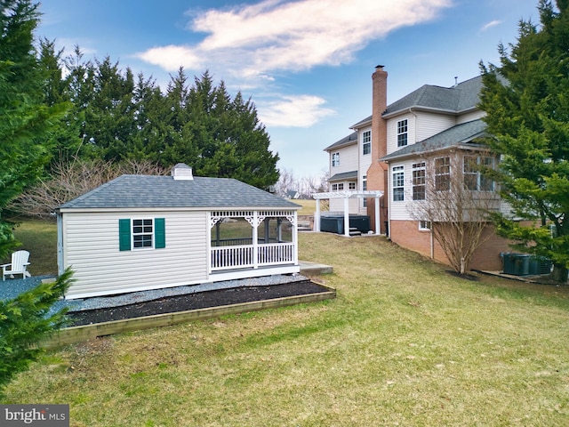 back of house with a hot tub, a yard, and central AC unit