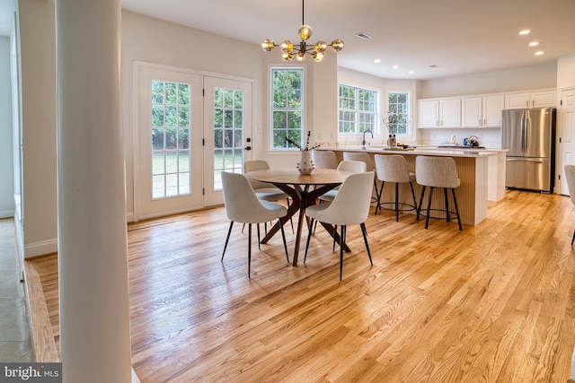 dining space with sink, a chandelier, and light hardwood / wood-style floors