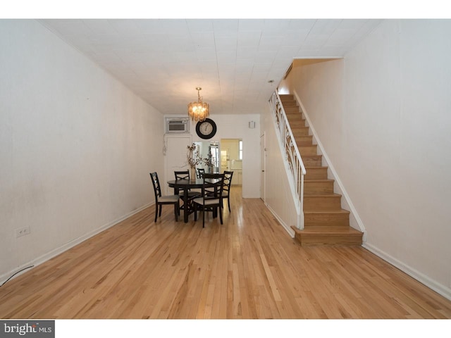 unfurnished dining area featuring an inviting chandelier, a wall unit AC, and light hardwood / wood-style floors