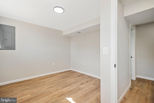 spare room featuring electric panel and light wood-type flooring