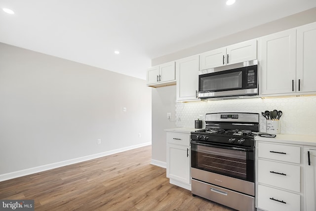kitchen with backsplash, light wood-type flooring, white cabinets, and appliances with stainless steel finishes