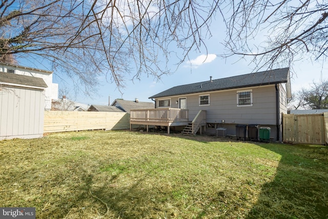 back of property with a wooden deck, central AC unit, and a lawn