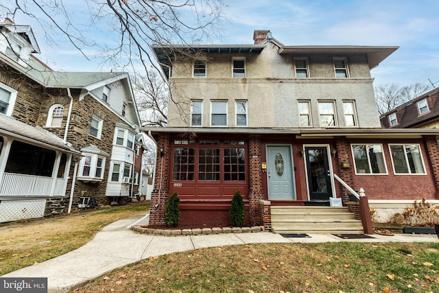 townhome / multi-family property with entry steps, a front lawn, and stucco siding