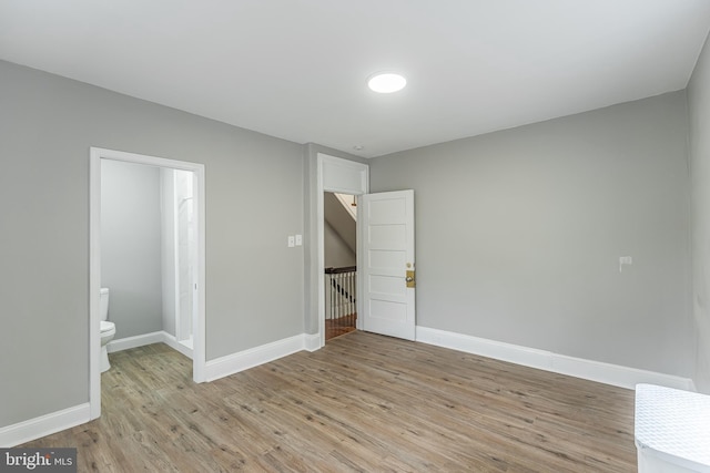 unfurnished bedroom featuring ensuite bathroom, light wood-type flooring, and baseboards