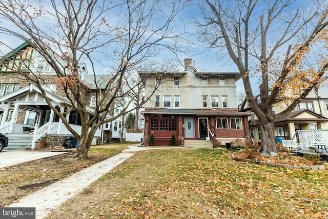 view of front facade with entry steps, a chimney, a front lawn, and brick siding