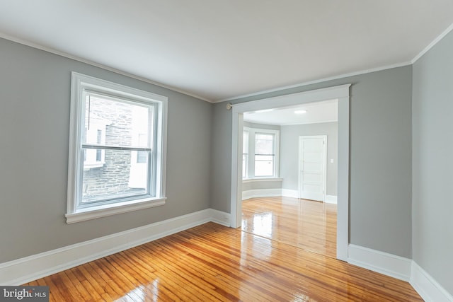 spare room featuring baseboards, crown molding, and light wood finished floors