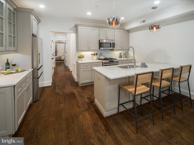 kitchen featuring sink, appliances with stainless steel finishes, tasteful backsplash, a kitchen bar, and decorative light fixtures