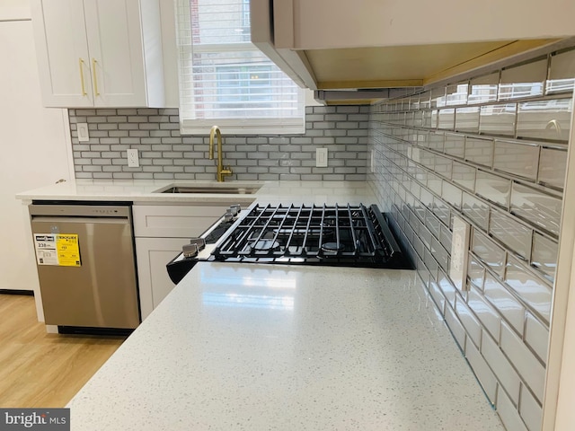 kitchen with white cabinetry, dishwasher, sink, backsplash, and stove