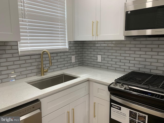 kitchen with sink, stainless steel appliances, light stone countertops, white cabinets, and decorative backsplash