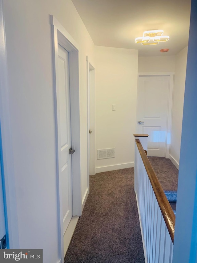 hall featuring dark colored carpet