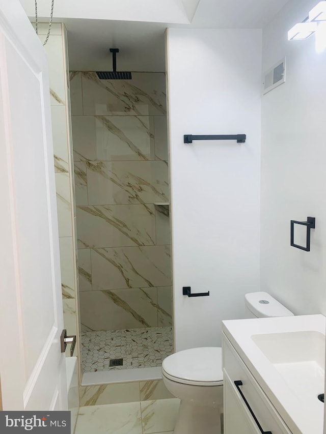 bathroom with vanity, toilet, and tiled shower