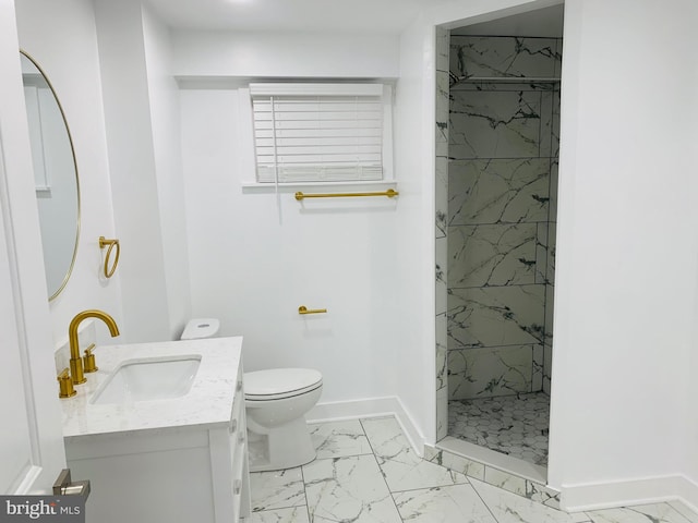 bathroom with tiled shower, vanity, and toilet