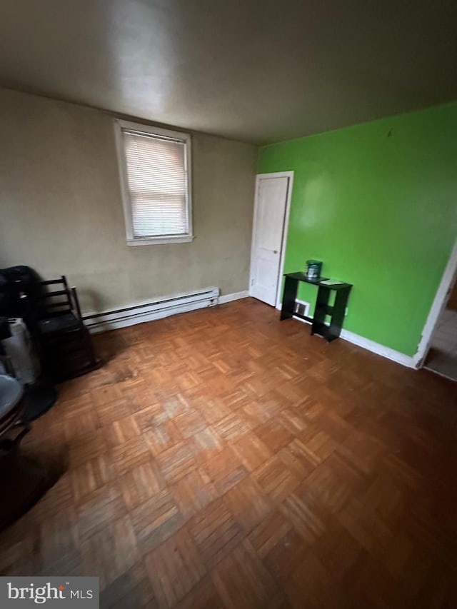 spare room featuring parquet flooring and a baseboard radiator