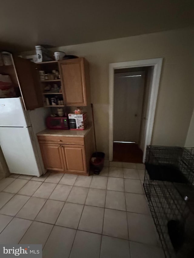 kitchen featuring white fridge, light tile patterned floors, and light brown cabinetry