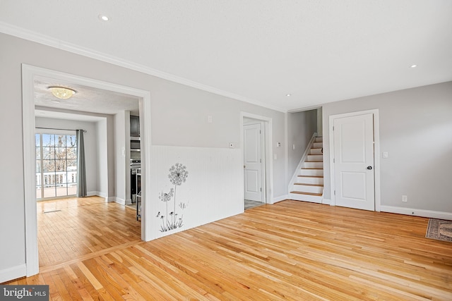 empty room featuring light hardwood / wood-style flooring, a textured ceiling, and ornamental molding