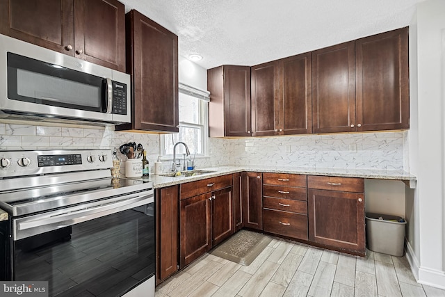 kitchen featuring sink, appliances with stainless steel finishes, tasteful backsplash, and light stone countertops