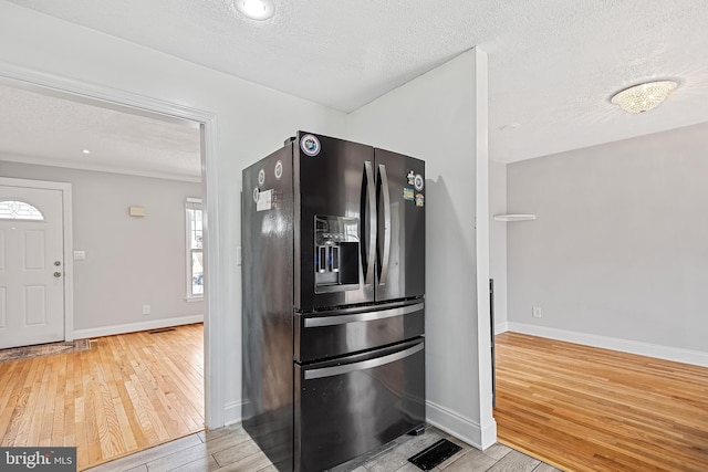 kitchen featuring black refrigerator with ice dispenser, light hardwood / wood-style flooring, and a textured ceiling