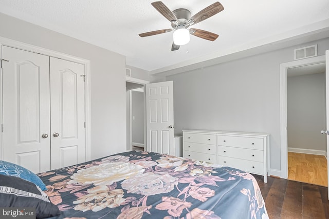 bedroom featuring dark hardwood / wood-style flooring, ceiling fan, a textured ceiling, and a closet