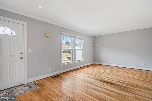 foyer entrance with ornamental molding, light hardwood / wood-style flooring, and a textured ceiling