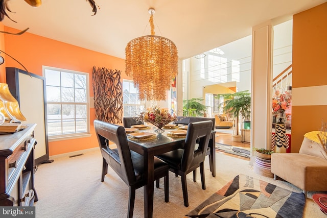 dining room featuring light colored carpet and an inviting chandelier